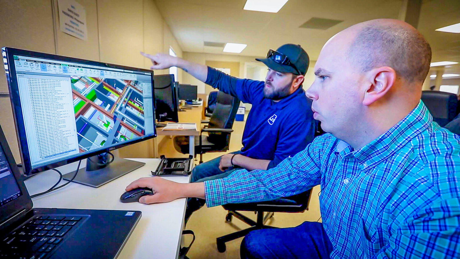 Two Sturgeon Electric employees look at a computer screen with BIM models.