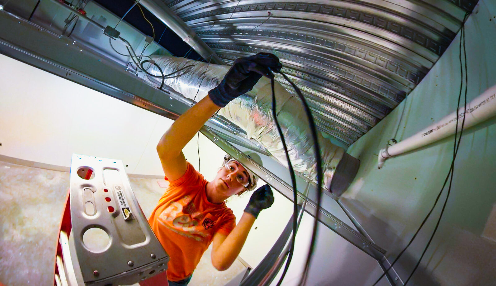 Huen worker on a ladder adjusting ceiling cables