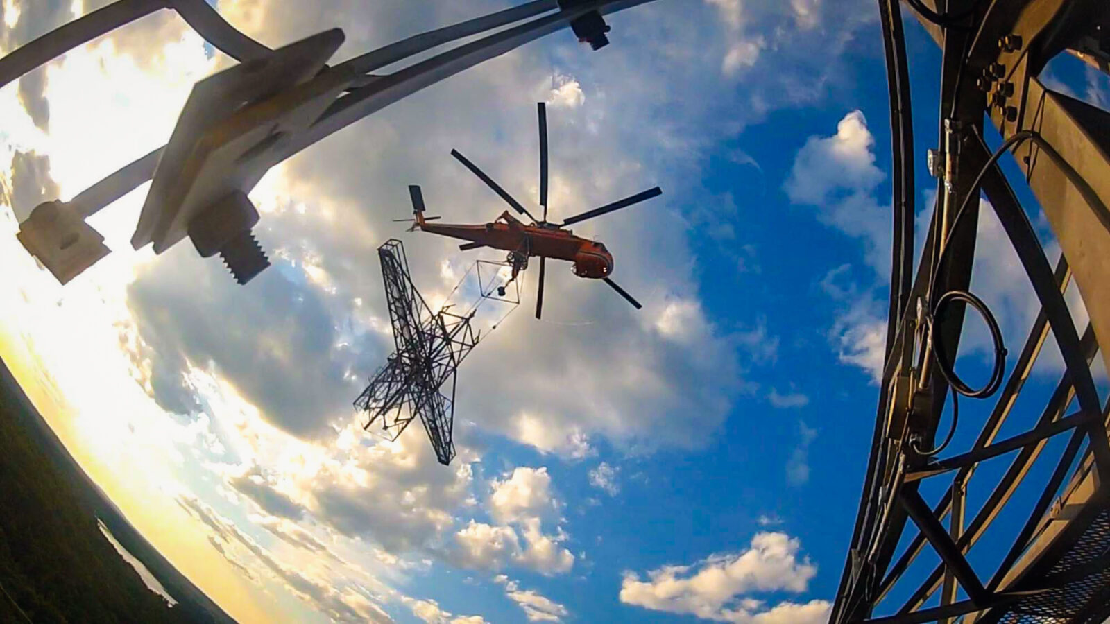 Orange helicopter carrying large piece of metal structure