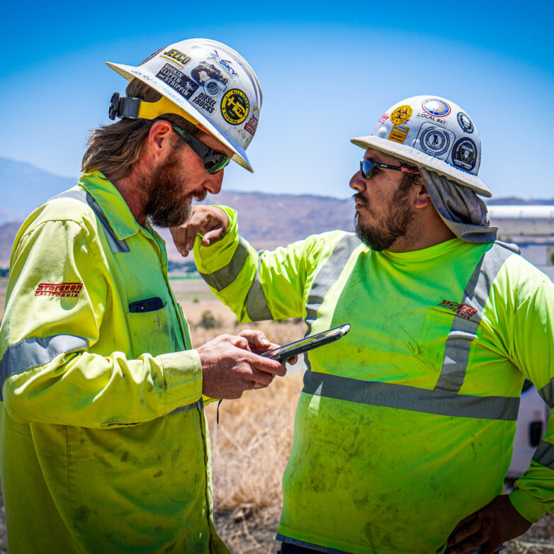 Two construction workers having a discussion while one is using a tablet