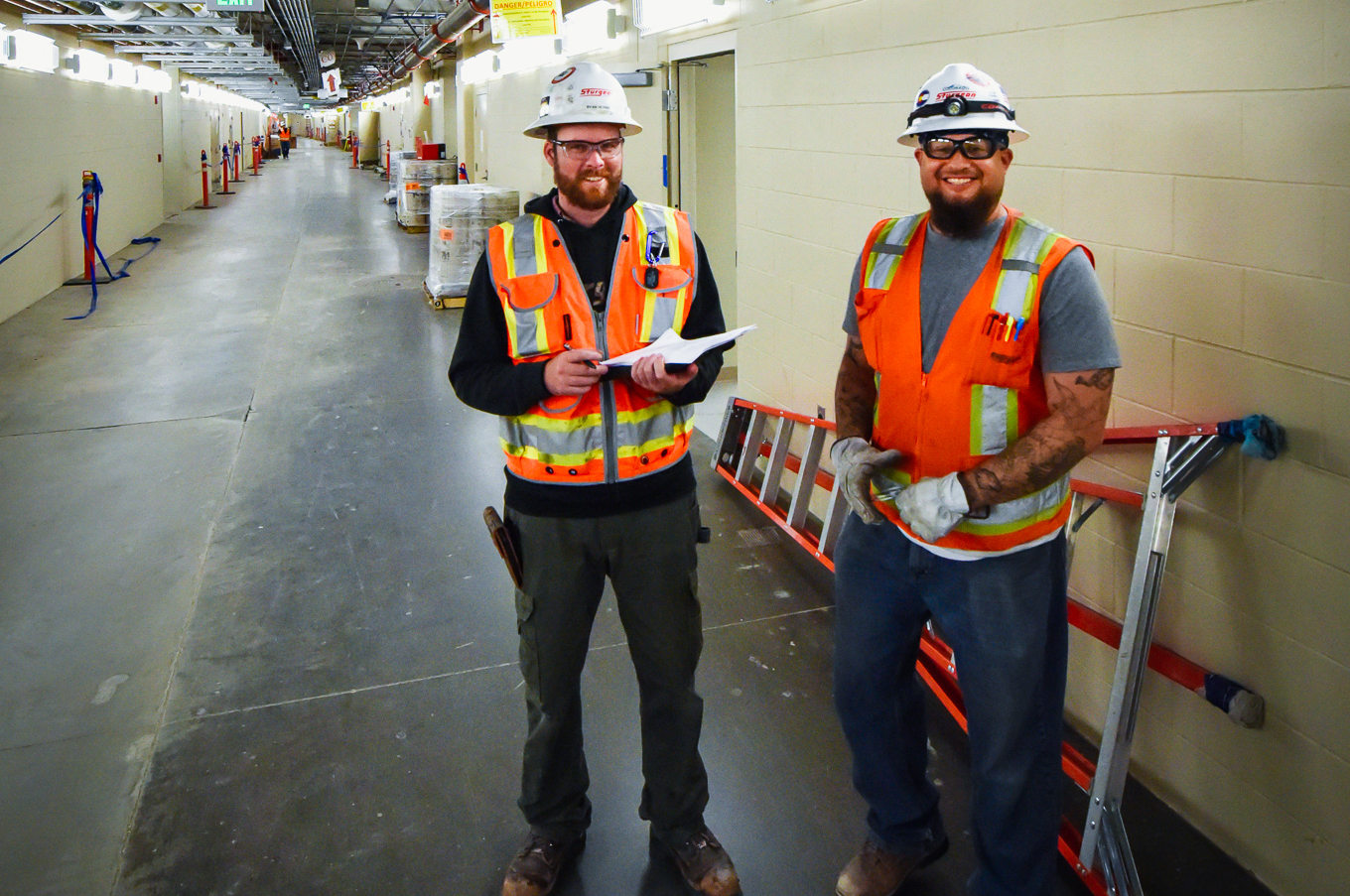 Two Sturgeon Electric workers smiling in a hallway